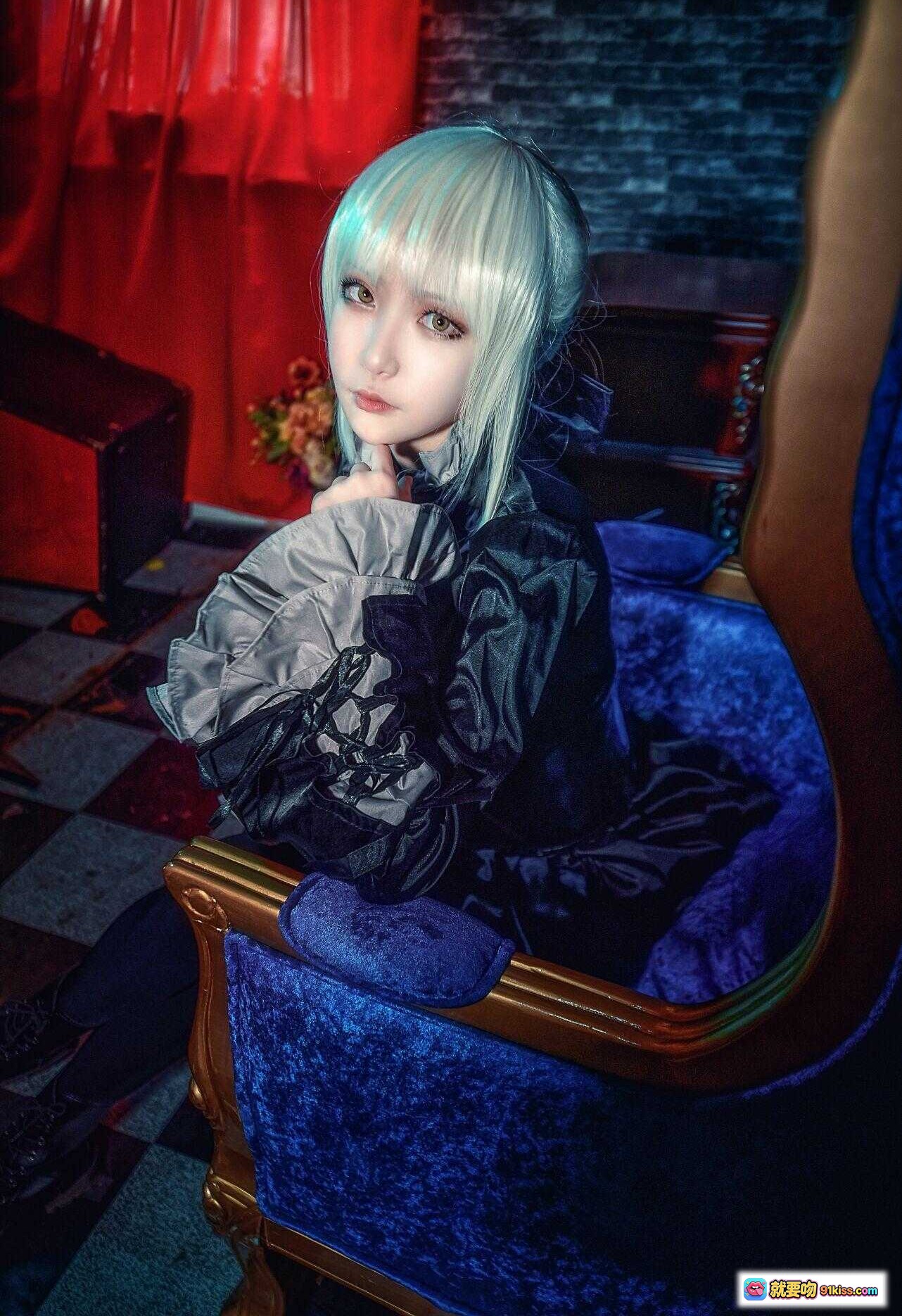 图片[1] - 黑SABER阿尔托莉雅cosplay写真｜哥特风蓝发少女坐姿优雅｜暗黑系华丽服饰搭配深蓝绒椅｜红幕背景氛围感十足 - 就要吻